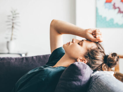 Sad and depressed woman sitting on sofa at home.