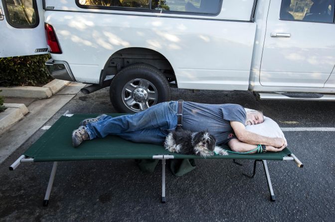 Doug Thomas and his dog Hanna rest November 9 while they await word if they can return to their Malibu Lake home.