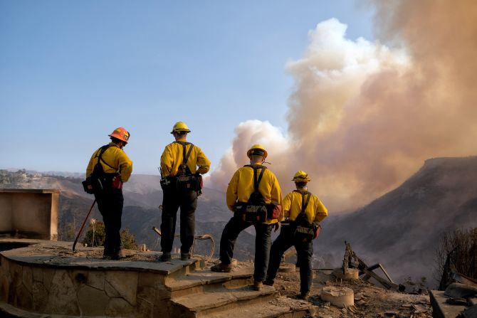 Culver City firefighters watch the Woolsey Fire from a burned home in Los Angeles.