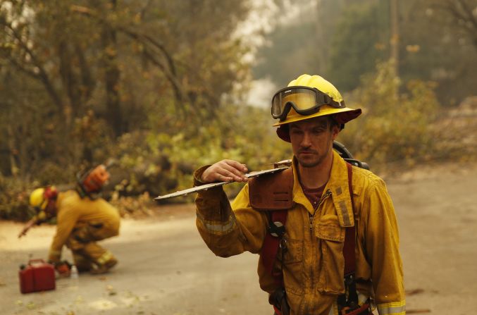 Shawn Slack carries a chainsaw on November 12 after trees burned in Paradise.