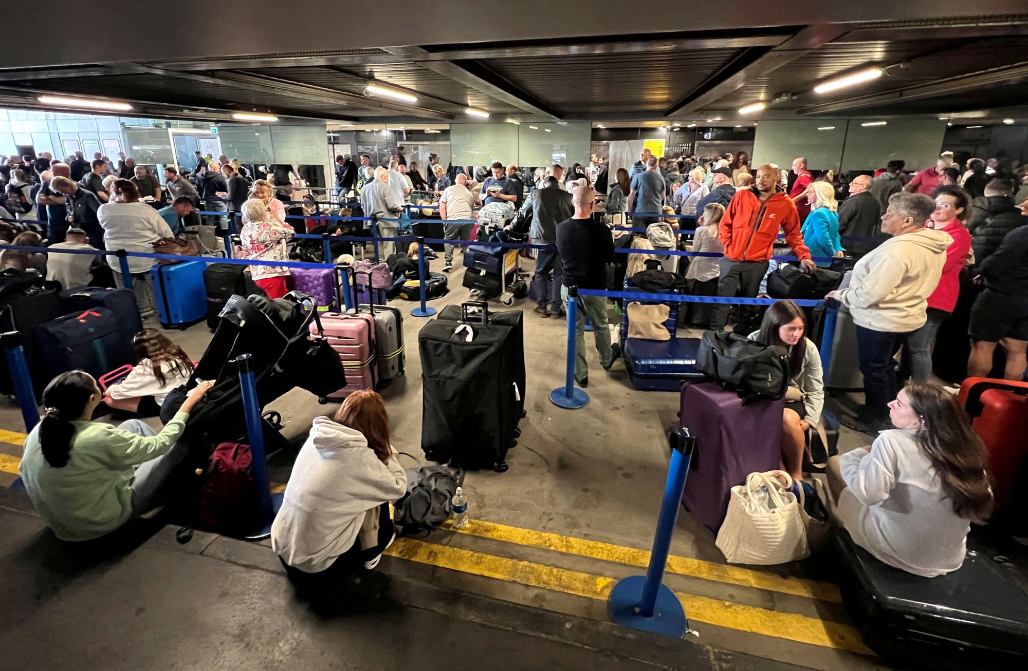 Passengers queue outside Terminal 1 after an overnight power cut led to disruptions and cancellations at Manchester Airport in Manchester, Britain, on June 23, 2024.