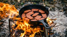 Grilled sausages on a campfire.