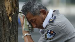 A security guard wearing an electric fan on his neck wipes his sweat on a hot day in Beijing, Monday, July 3, 2023. Heavy flooding has displaced thousands of people around China as the capital had a brief respite from sweltering heat. Beijing reported 9.8 straight days when the temperature exceeded 35 C (95 F), the National Climate Center said Monday. (AP Photo/Andy Wong)