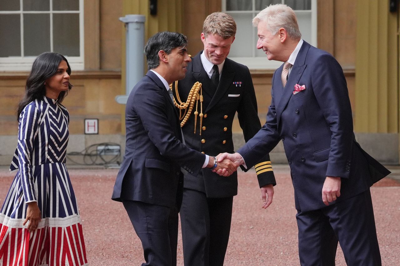 Sir Clive Alderton, Principal Private Secretary to The King and Queen, right, with Commander William Thornton, Royal Navy, Equerry to The King, second right, greet Rishi Sunak and his wife Akshata Murty, as he arrives at Buckingham Palace for an audience with King Charles III to formally resign as PM on July 5.