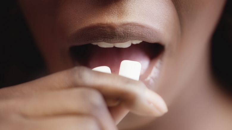 Black woman putting chewing gum in mouth, fresh flavor, healthy teeth, macro