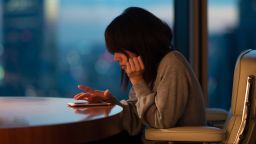 Japanese woman sitting at desk operating smartphone with fingers