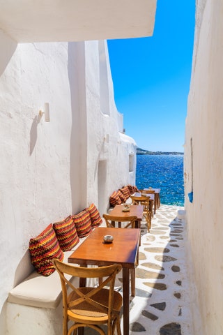 whitewashed houses and cobblestone street with ocean in background.