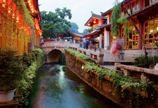 building next to fast moving river with bridge over water