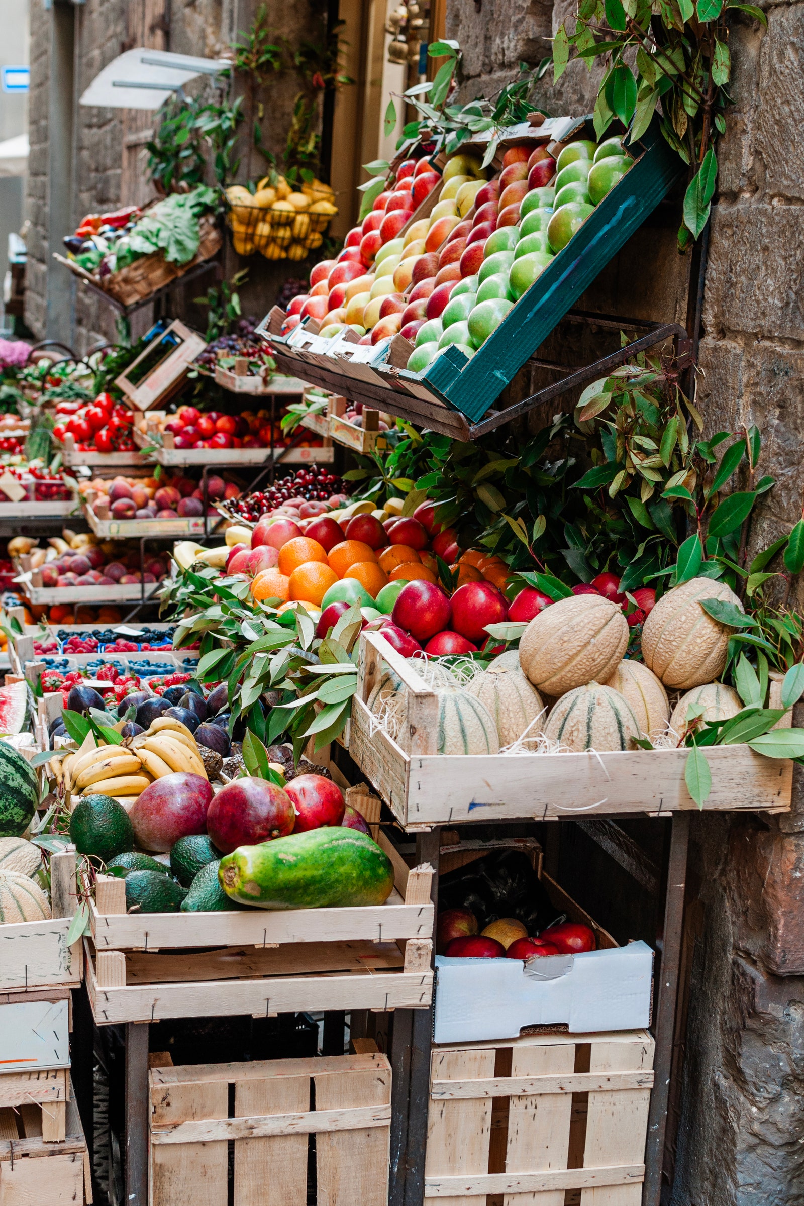 This image shows an outdoor display of fresh fruit for sale in Florence Italy. It features various fruits including...