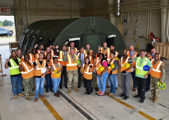 A group of employees poses for a photo in a warehouse.