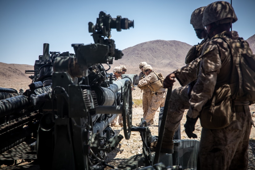 Marines prepare to fire a weapon in a desert-like area.