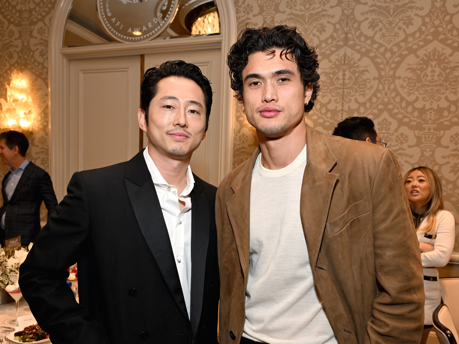 Image may contain Charles Melton Steven Yeun Blazer Clothing Coat Jacket Formal Wear Suit Adult Person and People