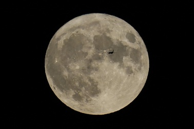A plane passes in front of the moon, Aug. 30, 2023, in Chicago.