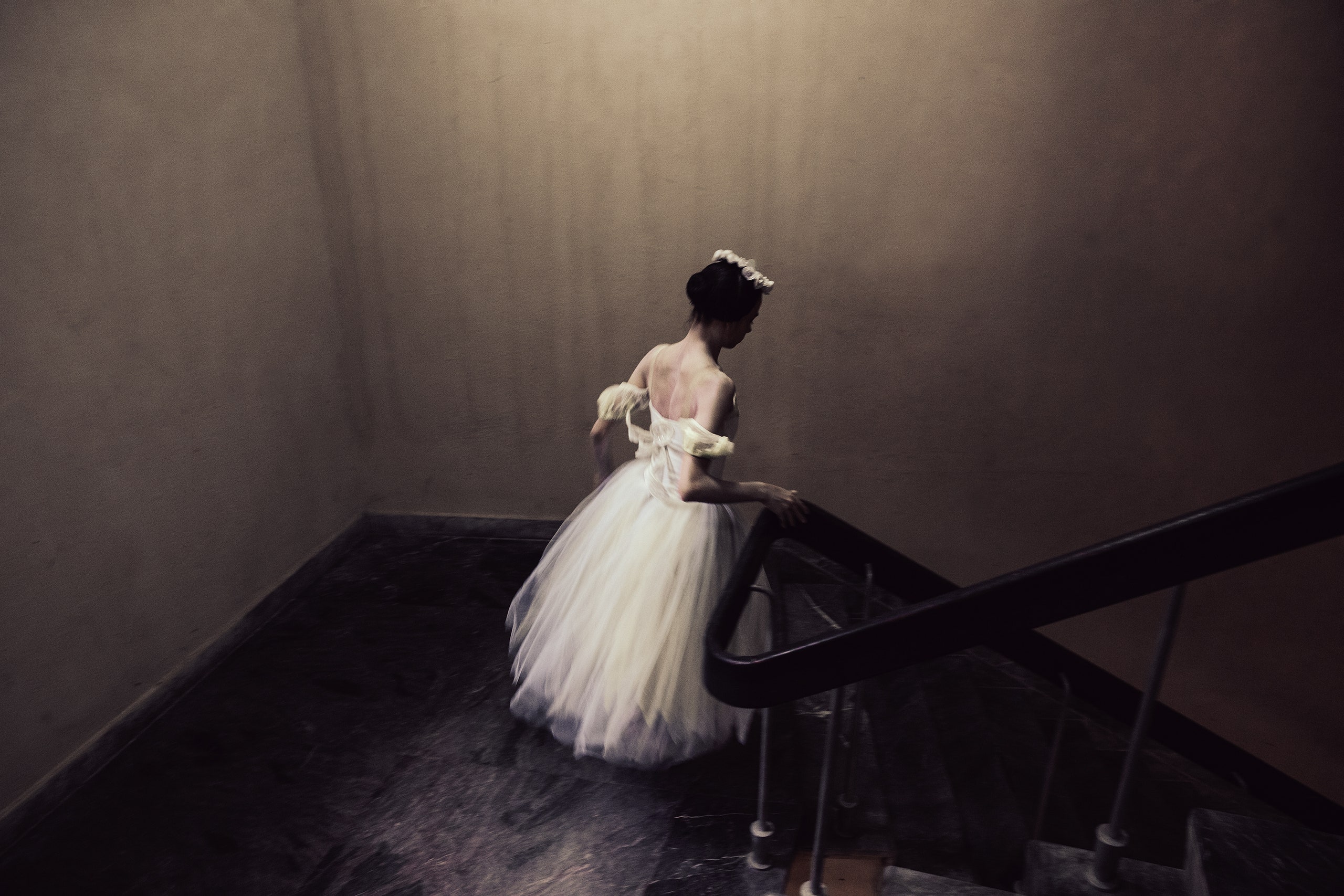 A ballerina in costume descending stairs.