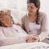 Young daughter supporting sick mother lying in hospital bed