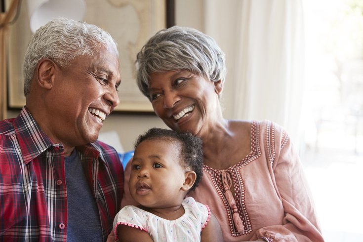 Purchased - Grandparents Sitting On Sofa With Baby Granddaughter At Home