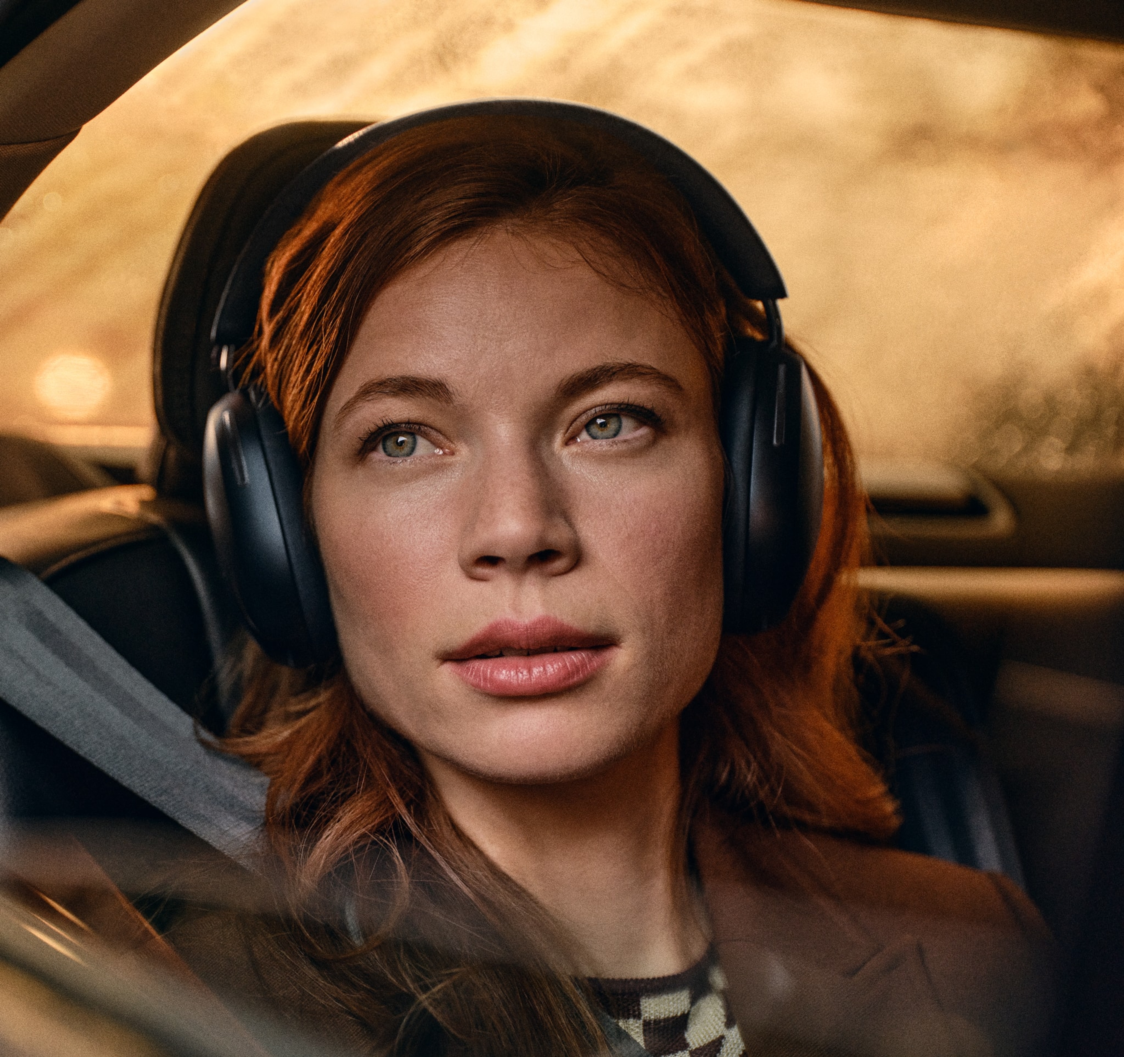 Female user wearing a pair of black Sonos Ace headphones while riding in a car