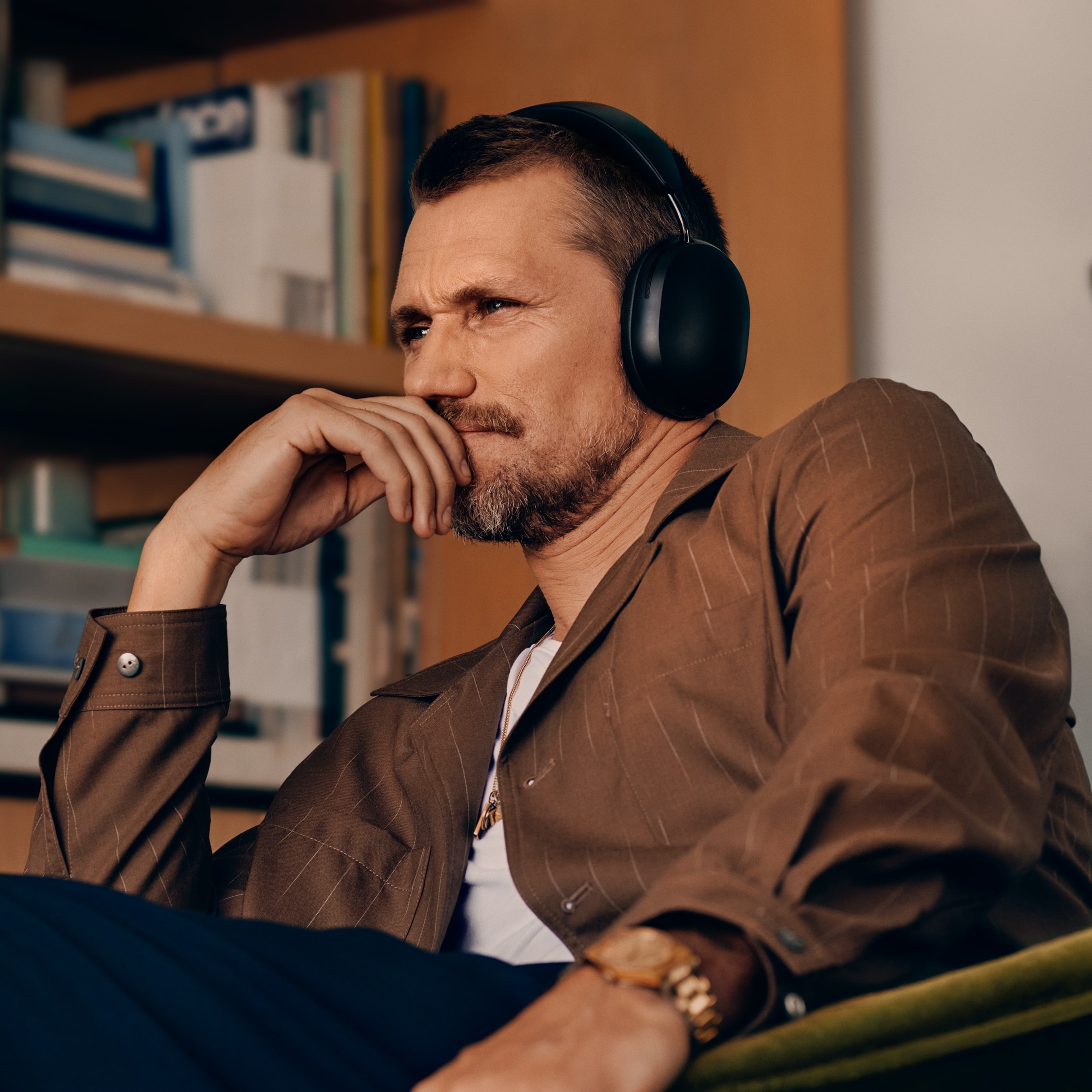 Male user wearing a pair of black Sonos Ace headphones while seated in a chair