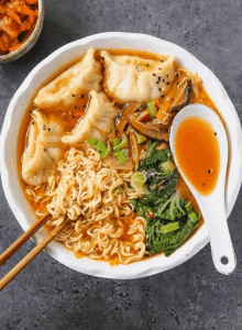 a bowl of ramen soup with dumplings and a spoon