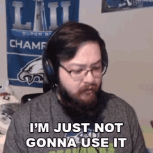 a man with a beard wearing headphones and glasses is sitting in front of a wall with a super bowl banner .