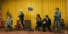 a group of people are standing in front of a yellow curtain and a podium with a globe on it