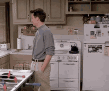 a man standing in a kitchen with a fridge that has a sticker on it that says ' coca cola '