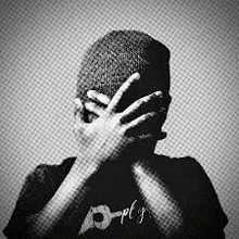 a black and white photo of a man covering his face with his hands .