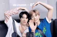 two young men making a heart shape with their hands in front of a hyundai sign