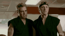 two men are standing next to each other in a gym wearing karate uniforms .