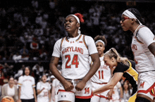 a maryland basketball player wearing number 24 stands in front of her teammates