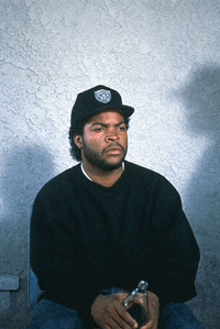 a man wearing a hat with the word raiders on it sits in front of a wall