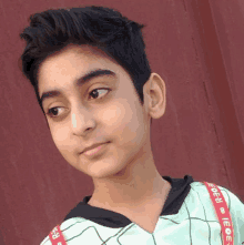 a young boy is standing in front of a red wall .