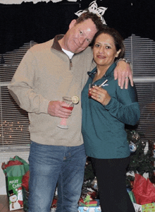 a man and a woman are posing for a picture in front of a merry christmas bag