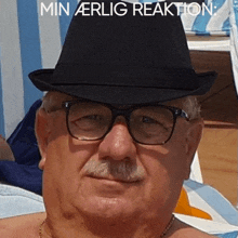 a man wearing glasses and a hat with the words min aerlig reaktion written below him