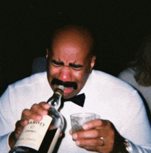 a man in a tuxedo is crying while holding a bottle of harveys