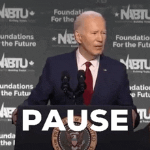 a man in a suit and tie is giving a speech at a podium with the word pause written on it .