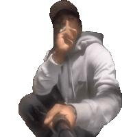 a man wearing a hat and a hoodie is kneeling down and smoking