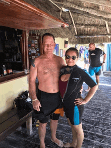 a man and a woman are posing for a picture and the woman is wearing a wetsuit with the letter o on it