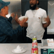 a man and a woman are standing next to each other in a kitchen with a can of uber eats on the counter