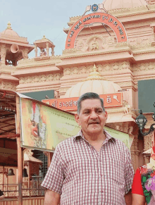 a man in a plaid shirt stands in front of a temple with a sign that says ' o ' on it