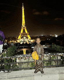 a man standing in front of the eiffel tower holding a purse