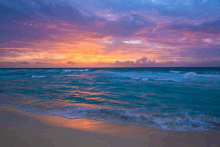 a sunset over a beach with waves crashing on the sand