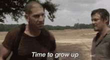 two men are standing next to each other in a field and one of them is talking to the other .