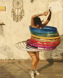 a woman is spinning a bunch of colorful hula hoops in front of a wall with a dream catcher on it