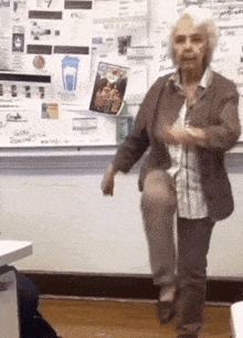 an older woman is standing on one leg in front of a white board with a picture of a blue cup on it