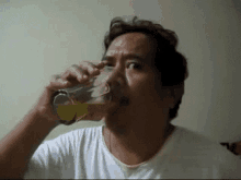 a man is drinking a glass of liquid from a bottle .