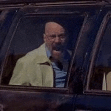 a man with a beard is sitting in a car and looking out the window .