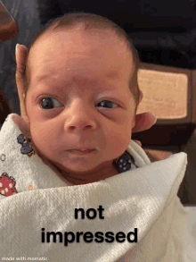 a baby is wrapped in a white blanket with the words " not impressed " on the bottom