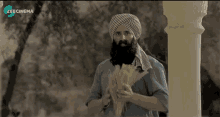 a man with a beard is holding a bunch of wheat in front of a screen that says zee cinema