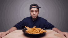 a man sitting at a table with a plate of french fries on it